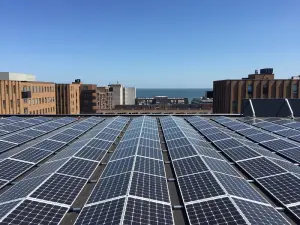 Referentie: Oost-west zonnepanelen opstelling voor maximale opbrengst Oost-west opstelling zonnepanelen op plat bedrijfsdak met uitzicht op zee - Solarnation België